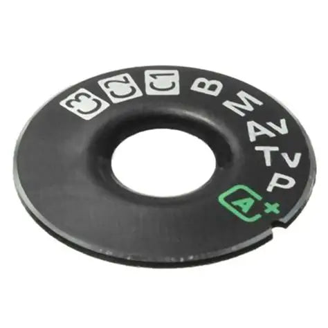 Black plastic camera mode dial interface cap with printed mode icons and green indicator