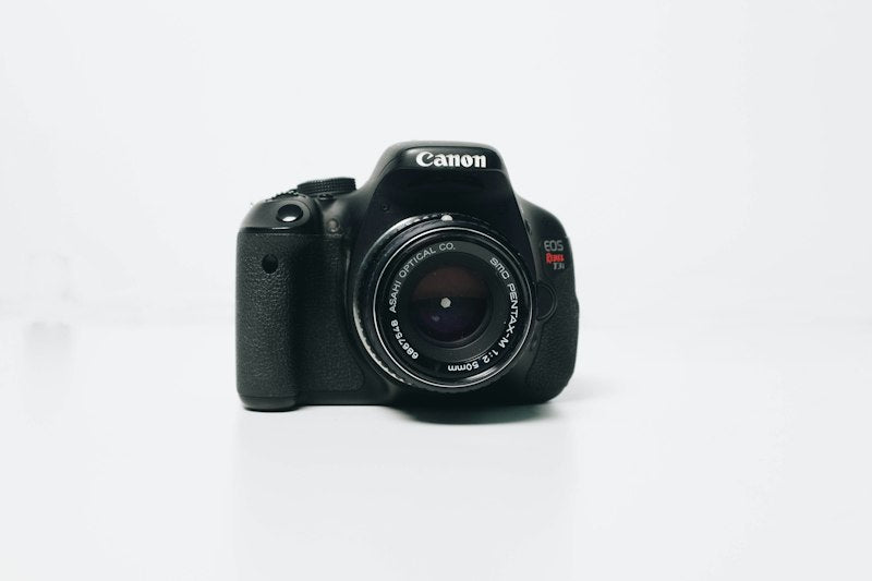 Black Canon DSLR camera body with mounted lens, front view