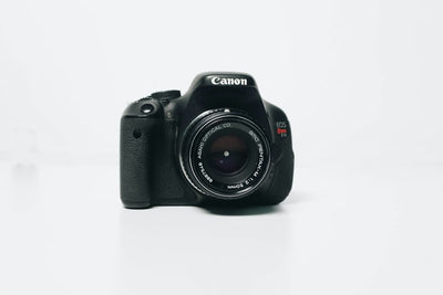Black Canon DSLR camera body with mounted lens, front view