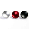 Round metal shutter release button caps in silver, red, and black